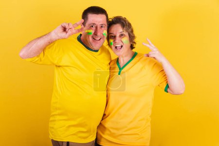 Photo for Adult couple, soccer fans from brazil isolated on yellow - Royalty Free Image