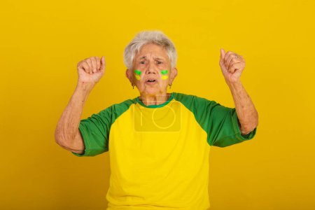Photo for Elderly woman, soccer fan from Brazil, cheering and vibrating, screaming goal - Royalty Free Image