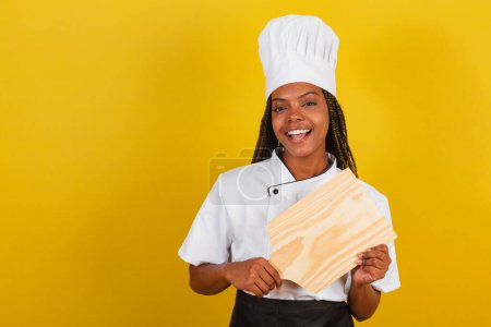 Photo for Young afro brazilian woman, cook, holding wooden board for gastronomy. - Royalty Free Image