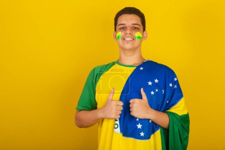 Téléchargez les photos : Jeune Brésilien fan de foot. habillé en vert, comme avec le drapeau du Brésil. - en image libre de droit