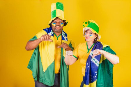 Foto de Pareja, mujer pelirroja y hombre negro, hinchas del fútbol brasileño. No me gusta, pulgar hacia abajo, negativo. - Imagen libre de derechos
