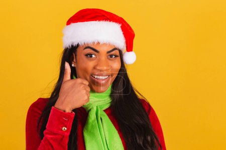 Téléchargez les photos : Belle femme brésilienne noire, vêtue de vêtements de Noël, Père Noël claus, genre, signe positif. - en image libre de droit