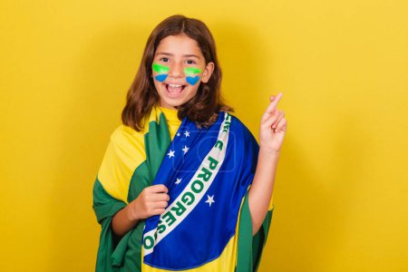 Photo for Brazilian caucasian child soccer fan, fingers crossed, cheering, wishing, hopeful. World Cup. Olympics. - Royalty Free Image