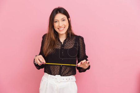Photo for Beautiful Brazilian Caucasian Woman, Pink Background, Holding Tape Measure, Nutritionist, Aesthetics, Measures, Quality of Life and Health. - Royalty Free Image