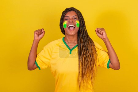 Téléchargez les photos : Jeune femme fan de football brésilien. célébrer, vibrer. Brésil équipe de football. - en image libre de droit