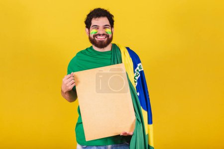 Téléchargez les photos : Homme caucasien avec barbe, brésilien, fan de football du Brésil, montrant signe pour annonces, textes et publicités. - en image libre de droit