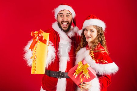 Photo for Brazilian couple, dressed in Christmas clothes, Santa Claus, holding gifts. - Royalty Free Image