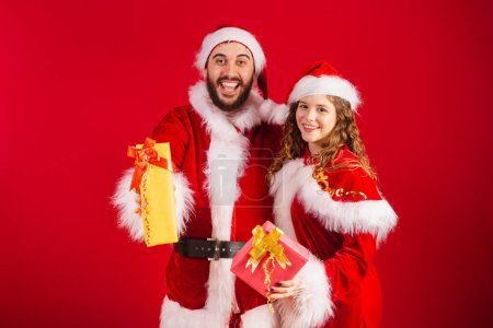 Téléchargez les photos : Couple brésilien, vêtu de vêtements de Noël, Père Noël, tenant des cadeaux. - en image libre de droit