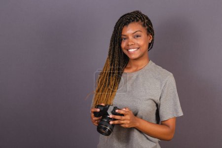 Photo for Young afro brazilian woman, photographer, smiling, holding photo camera. - Royalty Free Image