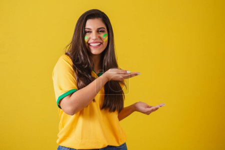 Téléchargez les photos : Femme supporter du Brésil, Coupe du monde 2022, championnat de football, présentation du produit avec les mains à droite. - en image libre de droit