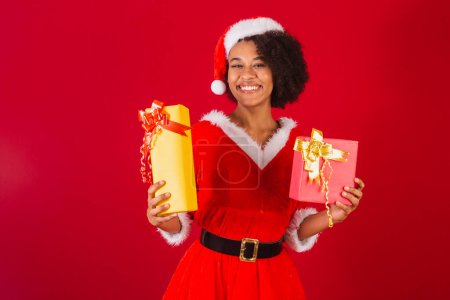 Photo for Beautiful black brazilian woman, dressed as santa claus, mama claus, holding two gifts - Royalty Free Image
