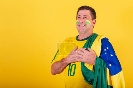Téléchargez les photos : Homme adulte, fan de football brésilien, portant le drapeau, chantant l'hymne national - en image libre de droit