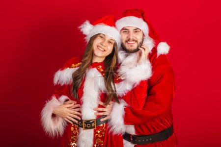 Foto de Pareja brasileña con ropa de Navidad, Santa Claus. abrazado románticamente. - Imagen libre de derechos