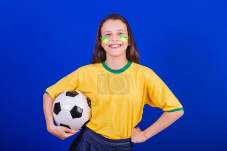 Téléchargez les photos : Jeune fille, fan de football du Brésil. tenant le ballon de football. - en image libre de droit