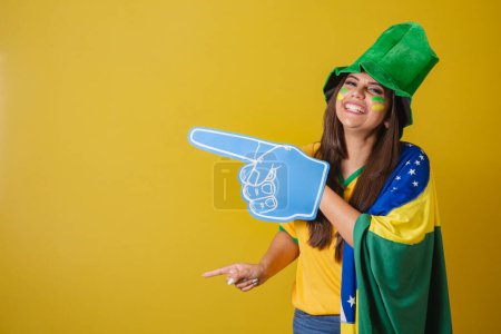 Photo for Woman supporter of Brazil, World Cup 2022, pointing with foam finger to the left. - Royalty Free Image