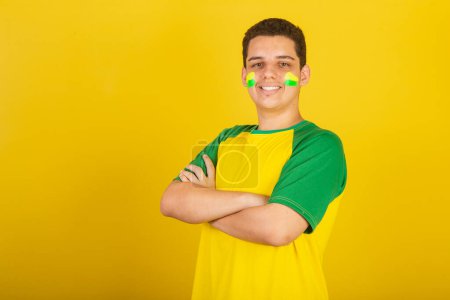 Foto de Joven aficionado al fútbol brasileño. vestidos de verde, y amarillos, brazos cruzados. - Imagen libre de derechos