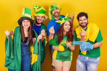 Téléchargez les photos : Groupe d'amis, les fans de football du Brésil, en utilisant le drapeau brésilien, appeler avec les mains, venez. Soyez les bienvenus. invitant. - en image libre de droit