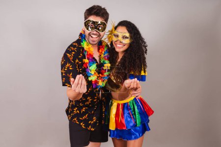 Téléchargez les photos : Couple brésilien, avec des vêtements de carnaval. invitant les mains. Viens, bienvenue.. - en image libre de droit