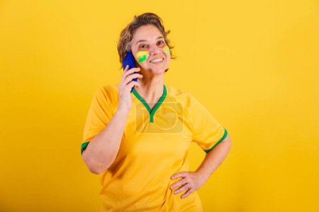 Photo for Adult adult woman, brazil football fan, smartphone, voice call. - Royalty Free Image