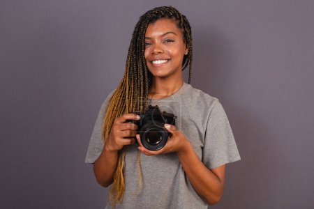 Foto de Joven mujer brasileña afro, fotógrafo, sonriendo, sosteniendo la cámara fotográfica. - Imagen libre de derechos