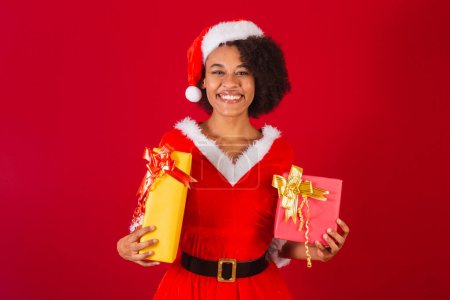 Téléchargez les photos : Belle femme brésilienne noire, habillée en Père Noël, maman Claude, tenant deux cadeaux - en image libre de droit