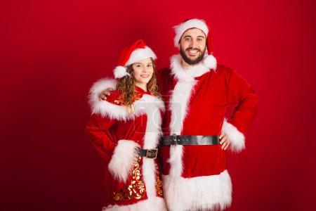 Téléchargez les photos : Couple brésilien, vêtu de vêtements de Noël, Père Noël, sourire à la caméra - en image libre de droit