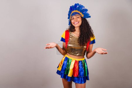 Foto de Hermosa mujer brasileña negra, con ropa frevo, carnaval. en tocado de plumas de carnaval. bienvenido, brazos abiertos. - Imagen libre de derechos