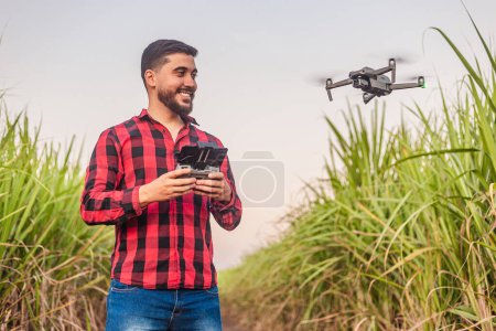 Photo for Young agricultural worker, agronomist, using drone for crop analysis, computerization, planting automation. Drone in agricultural use. - Royalty Free Image
