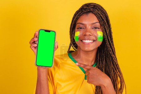 Photo for Black woman young brazilian soccer fan. holding cellphone, app, smartphone. close-up photo - Royalty Free Image