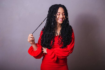 Foto de Hermosa brasileña negra, vestida de rojo. jugar con el cabello. - Imagen libre de derechos