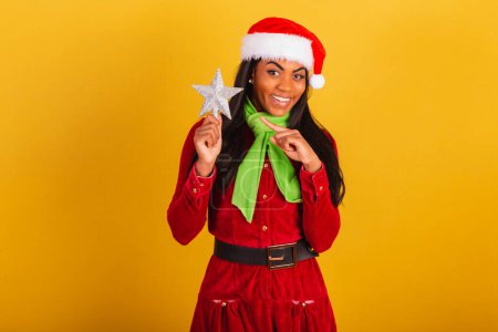Téléchargez les photos : Belle femme brésilienne noire, vêtue de vêtements de Noël, Père Noël claus, tenant étoile de Noël. - en image libre de droit