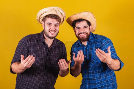 Photo for Two friends wearing typical clothes for the Festa Junina. Come here, calling with your hands. Inviting. - Royalty Free Image