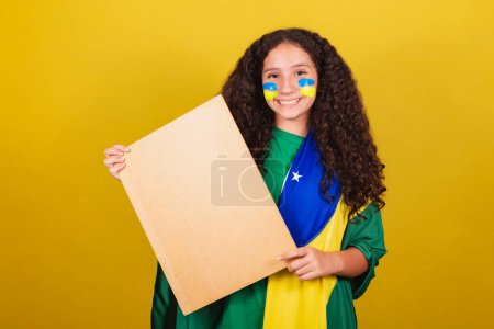 Photo for Brazilian caucasian girl soccer fan holding sign for announcement, text, advertisement. World Cup. Olympics. - Royalty Free Image