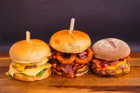 Foto de Tres hamburguesas artesanales, hechas con carne de res, queso y tocino. Anillos de cebolla frita. - Imagen libre de derechos