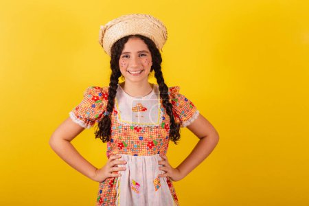 Photo for Girl wearing traditional orange clothes for festa junina. With hands on hips. Smiling. - Royalty Free Image