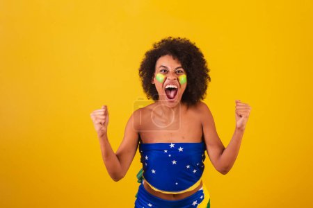Téléchargez les photos : Jeune femme noire fan de football brésilien. hurlant objectif - en image libre de droit