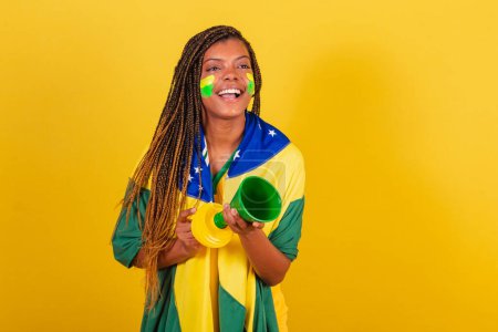 Photo for Black woman young brazilian soccer fan. using the horn, making noise, Partying championship. - Royalty Free Image
