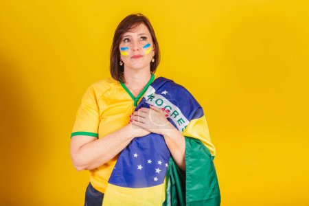 Téléchargez les photos : Femme rousse, fan de football brésilien. les mains sur la poitrine en chantant l'hymne national. Démocratie. - en image libre de droit