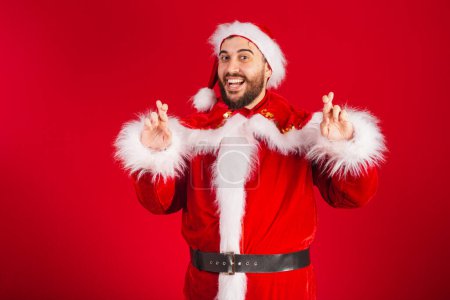 Photo for Brazilian man dressed in santa claus clothes, sign of luck, wishing, fingers crossed - Royalty Free Image