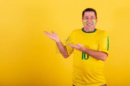 Foto de Hombre adulto, fanático del fútbol brasileño, presentando algo a su izquierda. - Imagen libre de derechos