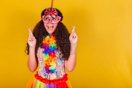Téléchargez les photos : Caucasienne, fille brésilienne habillée pour le carnaval. Les doigts croisés, souhaitant, espérant, plein d'espoir. - en image libre de droit