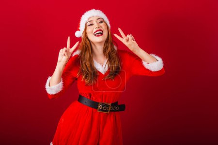Téléchargez les photos : Belle femme rousse brésilienne, vêtue de vêtements de Noël, le Père Noël. paix et amour, posant pour la photo. - en image libre de droit