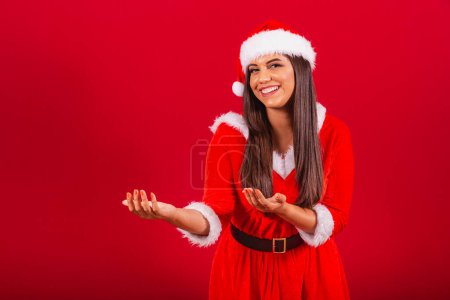Photo for Beautiful Brazilian woman dressed in Christmas clothes, Santa Claus. inviting hands. - Royalty Free Image