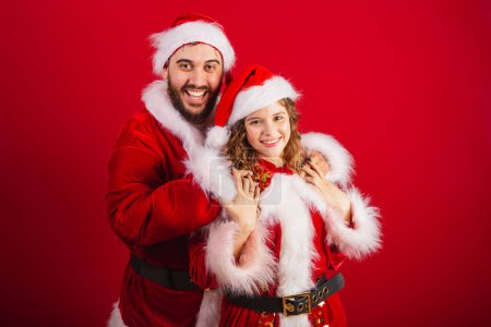 Photo for Brazilian couple, dressed in Christmas clothes, Santa Claus, hugging - Royalty Free Image