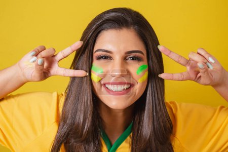 Foto de Acercamiento foto, Mujer partidaria de Brasil, Copa del Mundo 2022, campeonato de fútbol, dedos de la paz y el amor, extremadamente feliz. - Imagen libre de derechos