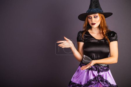 Foto de Ensayo de Halloween, mujer caucásica con disfraz de bruja. presentando algo con sus manos. - Imagen libre de derechos