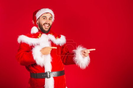Photo for Brazilian man, dressed in santa claus clothes, presenting product or text on the right - Royalty Free Image