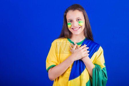 Photo for Young girl, soccer fan from Brazil. dressed in flag, singing national anthem. Gratitude. - Royalty Free Image