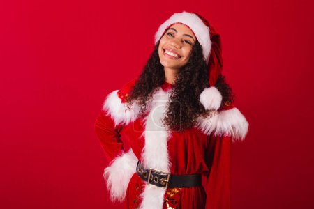 Photo for Beautiful brazilian black woman, dressed as santa claus, christmas clothes. smiling, thoughtful. - Royalty Free Image