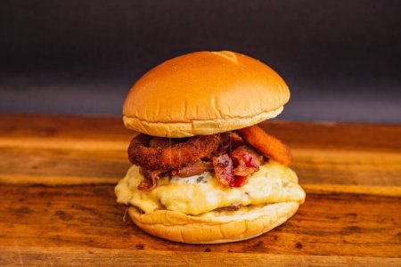 Foto de Deliciosa hamburguesa de pollo con queso mozzarella, tocino frito y aros de cebolla frita. - Imagen libre de derechos